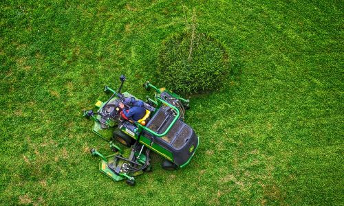 green and black ride on lawn mower on green grass field during daytime