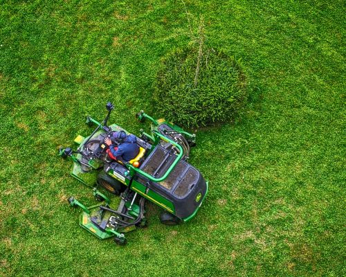 green and black ride on lawn mower on green grass field during daytime