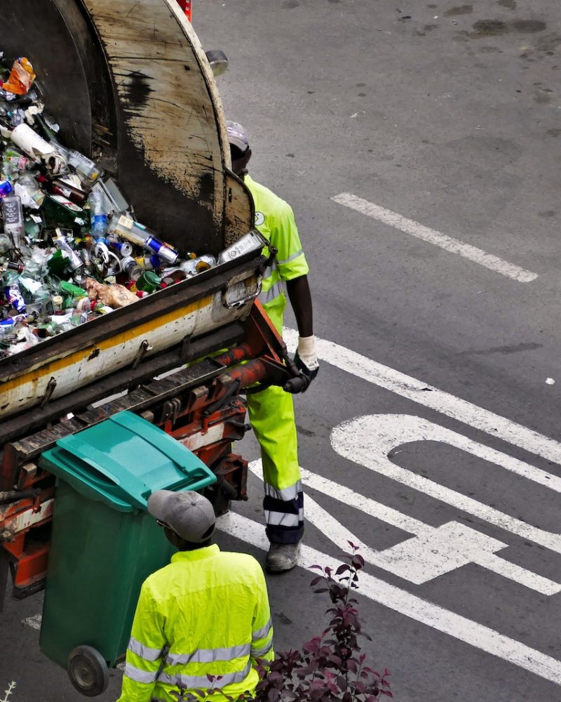people collecting trash in garbage truck